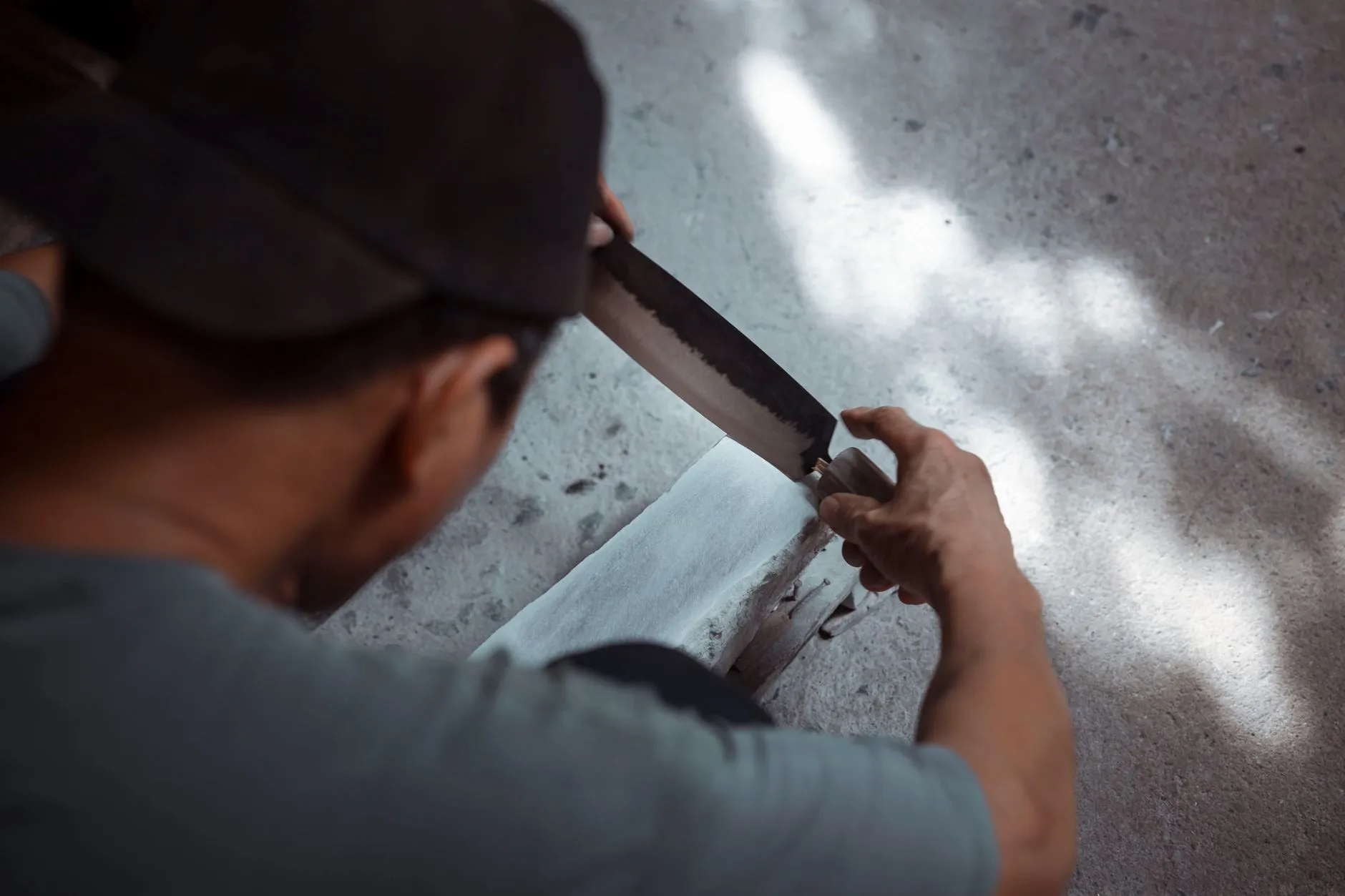 A skilled man sharpening a knife on a whetstone in a traditional manner.
